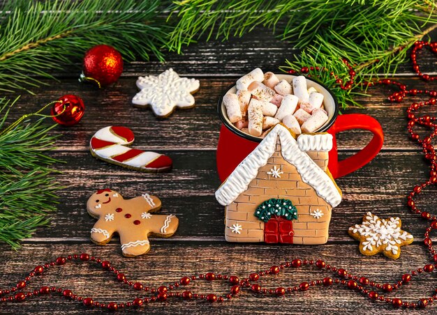 Red cup with marshmallow and gingerbread house Christmas composition with gingerbread cookies