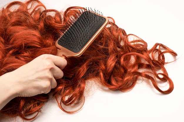 Red curly hair in woman hands with red nails Top0 view