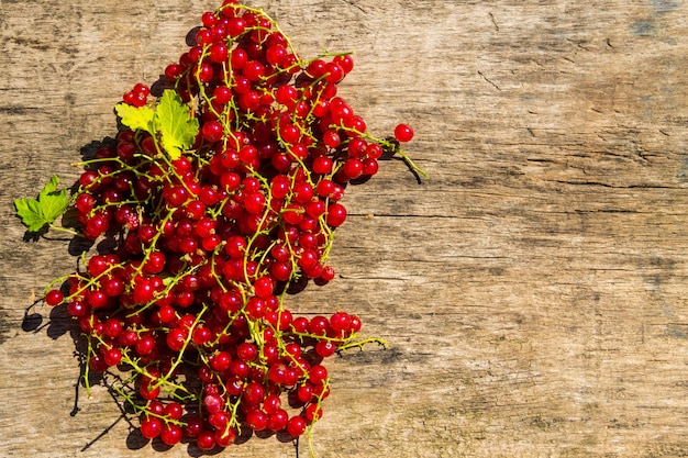 Red currant berries on rustic wooden background. Top view with copy space
