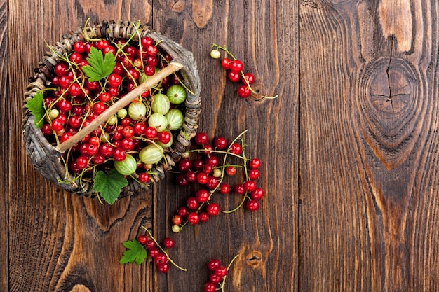 Red currantand and  gooseberry in the basket on wooden table