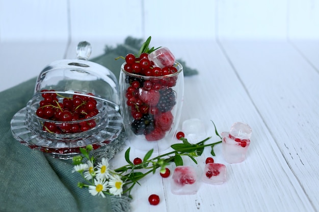 Foto ribes rosso in una tazza di vetro con foglie verdi