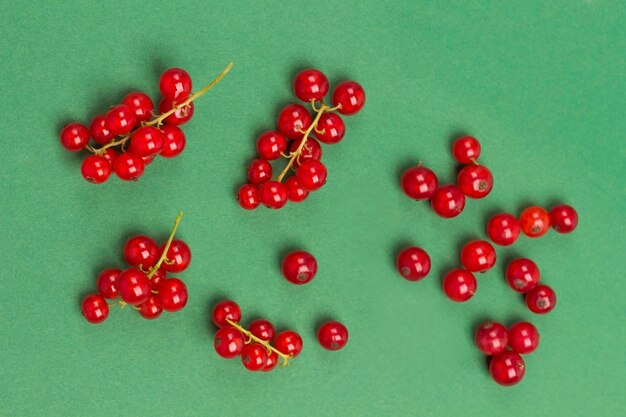 Red currants on green background Flat lay