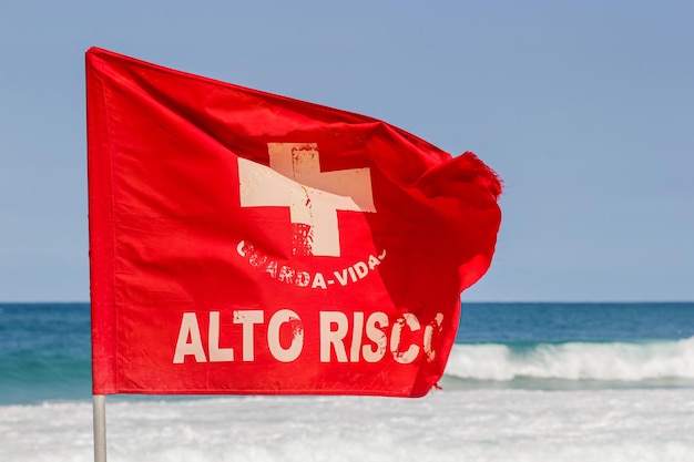 Bandiera rossa di segnalazione della corrente scritta ad alto rischio su una spiaggia a rio de janeiro in brasile