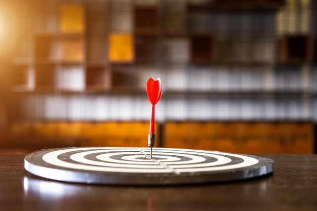 Red dart arrow hitting in the target center of dartboard on bullseye with sun light vintage style Target marketing and business success concept