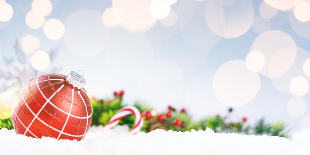 red decorative ball on the christmas tree on glitter bokeh background with golden twinkle lights merry christmas card