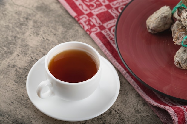 Красные вкусные сушеные фрукты хурмы и чашка чая на каменной поверхности