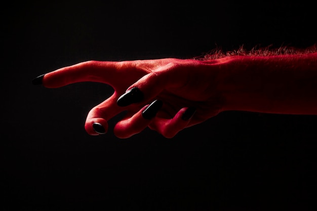 Red devil creepy halloween hand on a black background