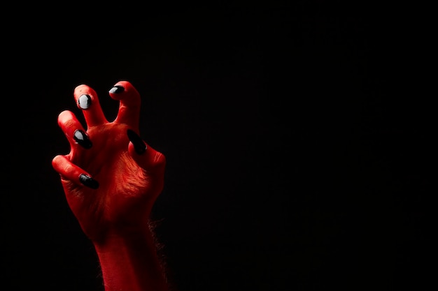 Red devil creepy halloween hand on a black background