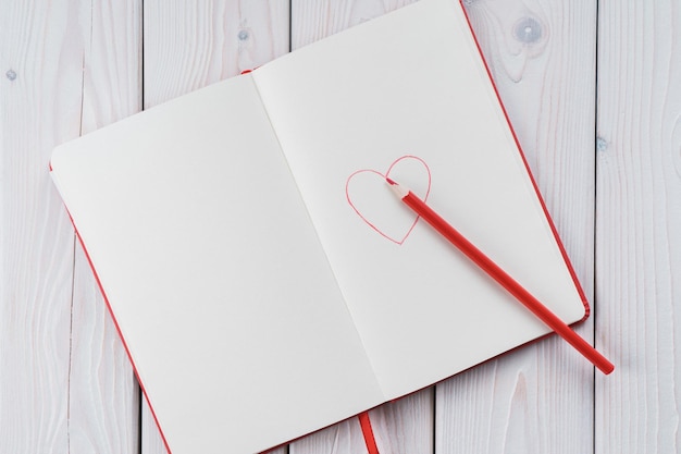 Red diary notebook with white papers craft pencil and red
drawing heart on page love letter message on valentines day