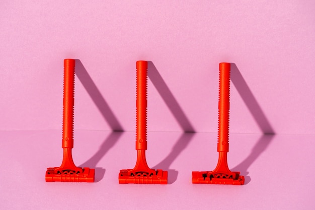 Red disposable razor on pink background, with copy space