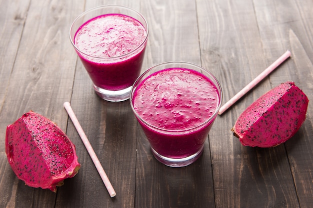 Red dragon fruit smoothie on wooden table.