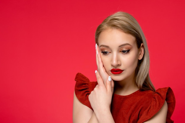 Abito rosso primo piano ragazza adorabile carina di classe in abito bordeaux con rossetto rosso che guarda in basso