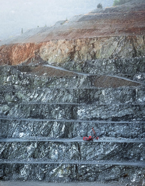 Red drilling machine on a bench of diabase quarry in misty morning