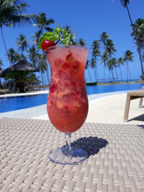 red drink on table against swimming pool