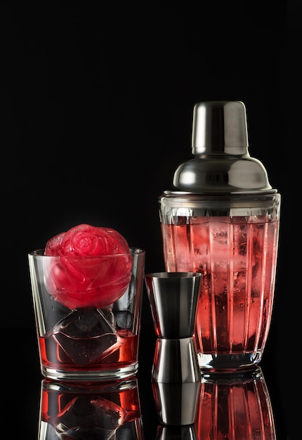 Red drink with ice and bar shaker black background Summer cold alcoholic soft drinks drinks and cocktails