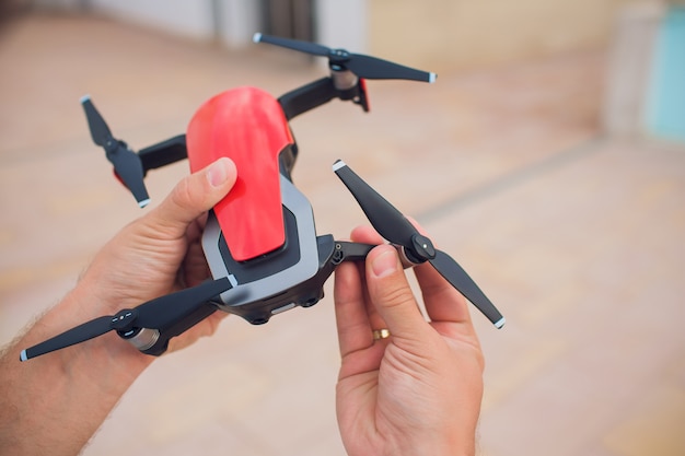 Red Drone catching control by man hands. lays out propellers