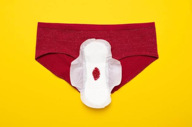 Red drop from beads on pants on yellow background menstruation period