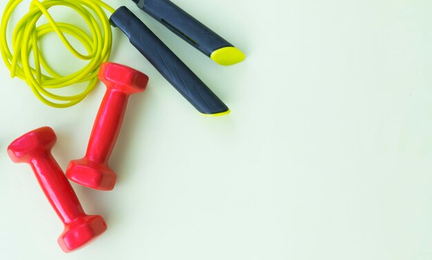 Photo red dumbbells and jump rope on a light background