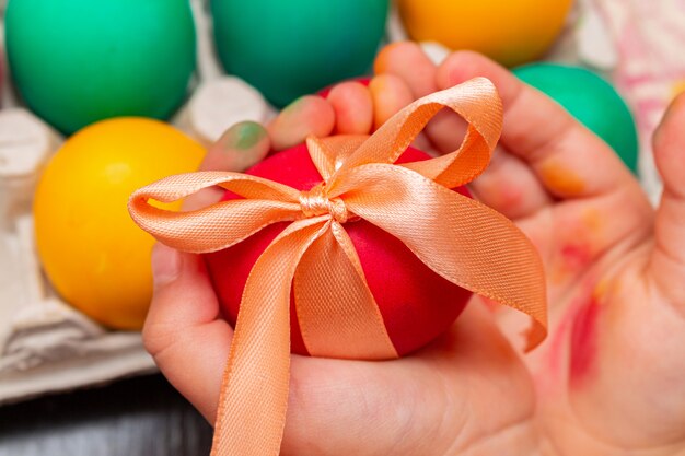 Red egg with bow in hands for the the Easter