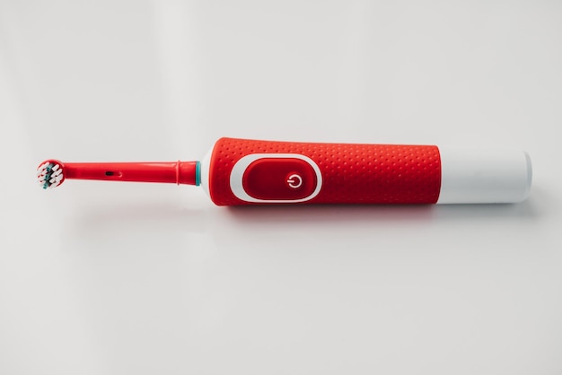 Red electric toothbrush on a white background