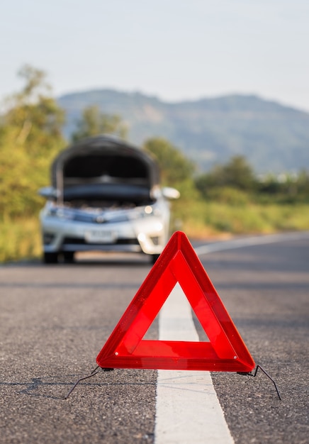 Red emergency stop sign and broken silver car on the road