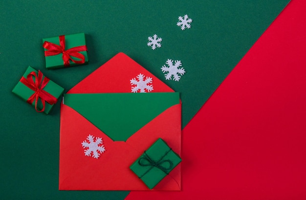 Red envelope, snowflakes and three Christmas gifts on a red-green