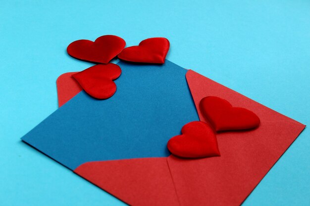 Photo red envelope with a blue sheet of paper and with hearts next to write text and send a letter for the holiday happy valentine's day