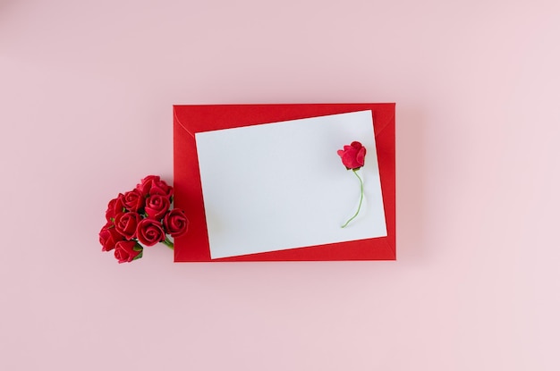 Red envelope with card and roses on pink background