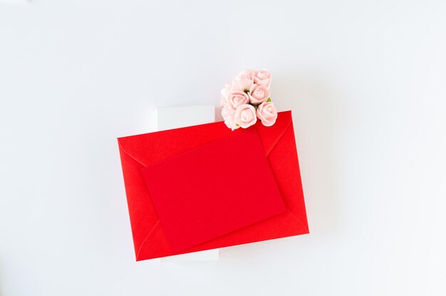 Red envelope with card and roses on white background