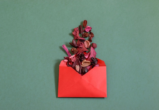 Red envelope with rose dry petals on the green background.