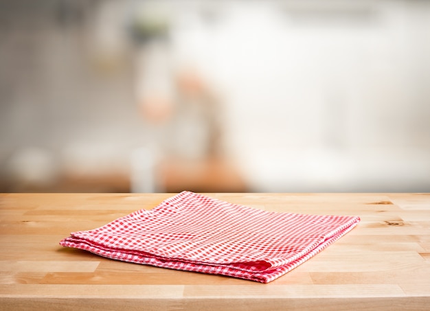 Red fabriccloth on wood table top on blur kitchen counter room background