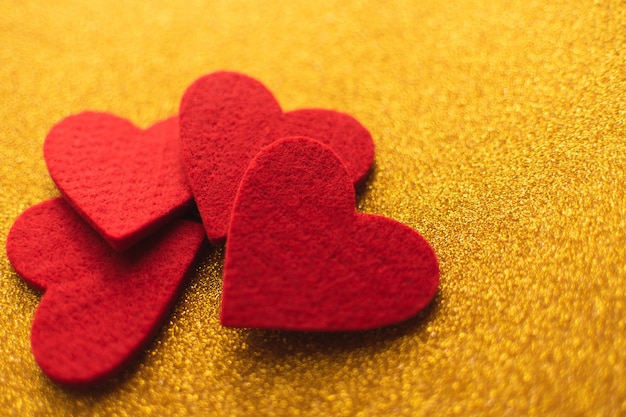 Red felt hearts on golden shiny surface