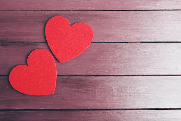 Red felt hearts on purple wooden background