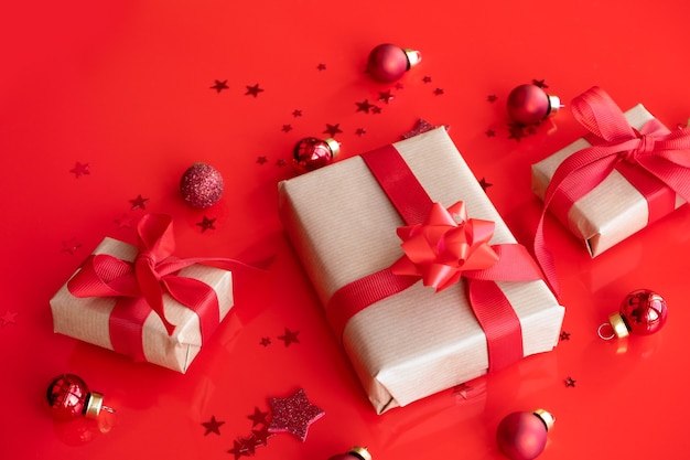 Red festive background gifts box with shiny stars and balloons top view.