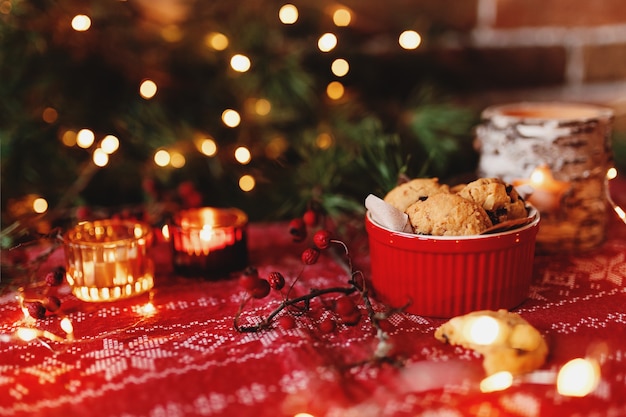 Red festive bowl full with christmas cookies blurred christmas fir tree lights