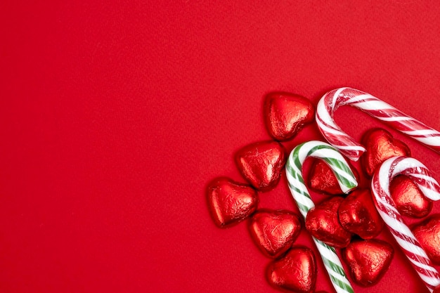 Red festive Christmas background with candy in the shape of hearts