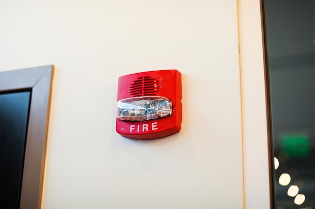 A red fire alarm on a white wall with a fire alarm on it.