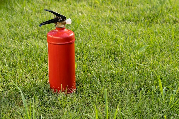 красный огнетушитель на зеленой траве