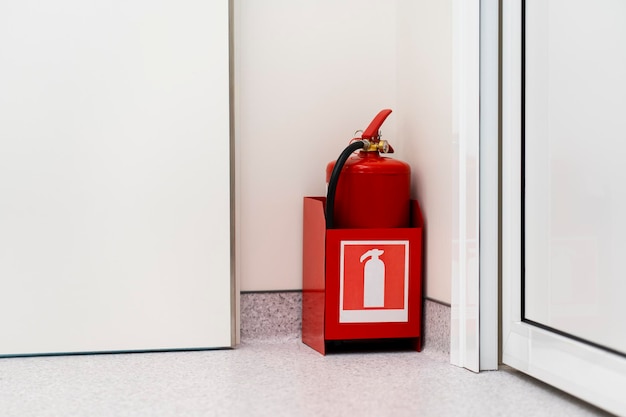 Red fire extinguisher stands in the corner of the room Life safety concept