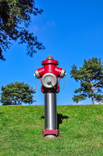 Red fire hydrant on field against blue sky