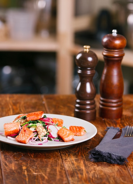 Red fish salmon with radish and spinach, served on white plate on wooden table. rustick style. View from above, top studio shot