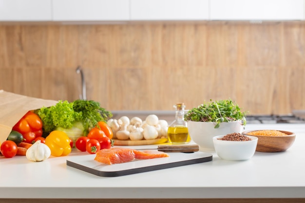 Red fish and various vegetables in kitchen