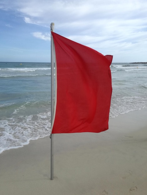 Foto bandiera rossa sulla spiaggia contro il cielo