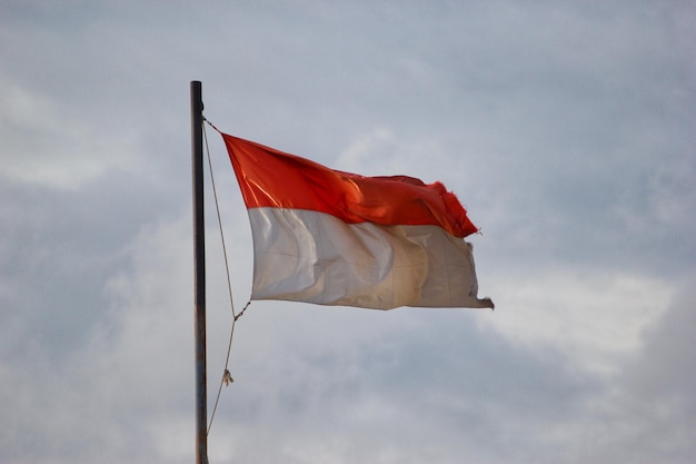 a red flag flies in front of a cloudy sky.