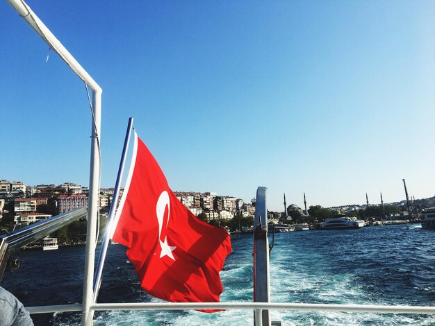 Red flag on sailboat against clear blue sky