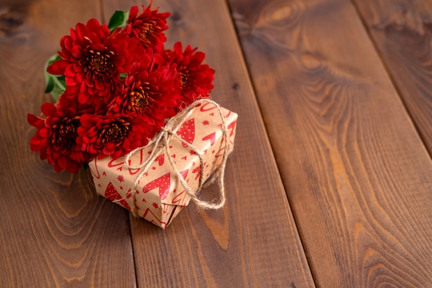 赤い花と木の板にクラフトギフト。バレンタインデーの背景。聖バレンタインの日カードのコンセプト