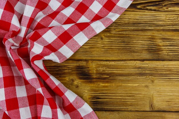 素朴な木製のキッチン テーブルの上に赤い折り畳まれた市松模様のナプキン上面コピー スペース