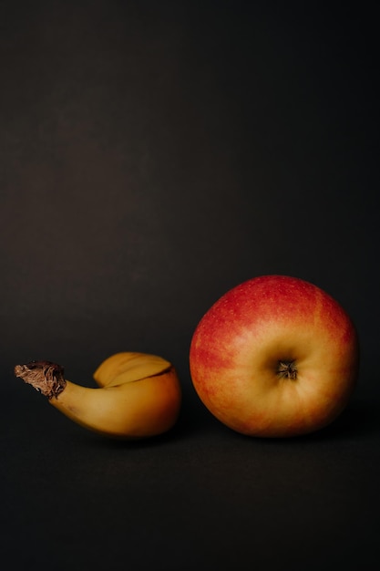 red fresh apple and banana on black background