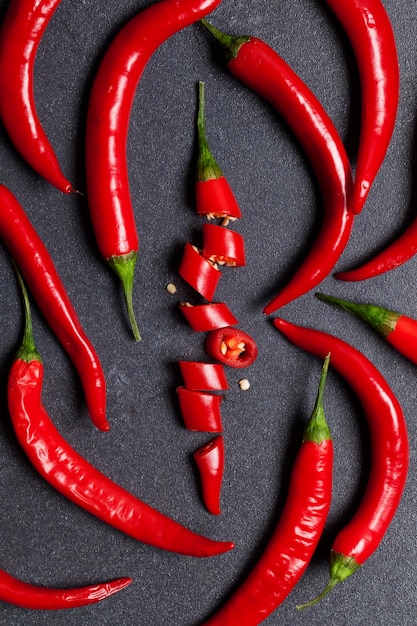 Red fresh chili pepper chopped into pieces on a dark slate background