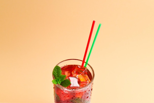 Красный свежий напиток со льдом, грейпфрутом и мятой на бежевом фоне. пространство для текста или дизайна.